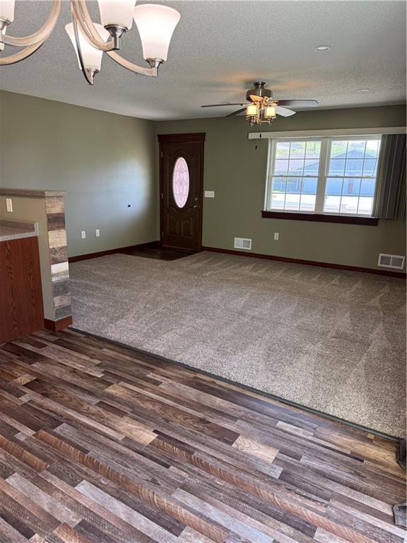 169 Amber View St, Menomonie, WI 54751 - unfurnished living room featuring a chandelier, baseboards, a ceiling fan, carpet floors, and a textured ceiling