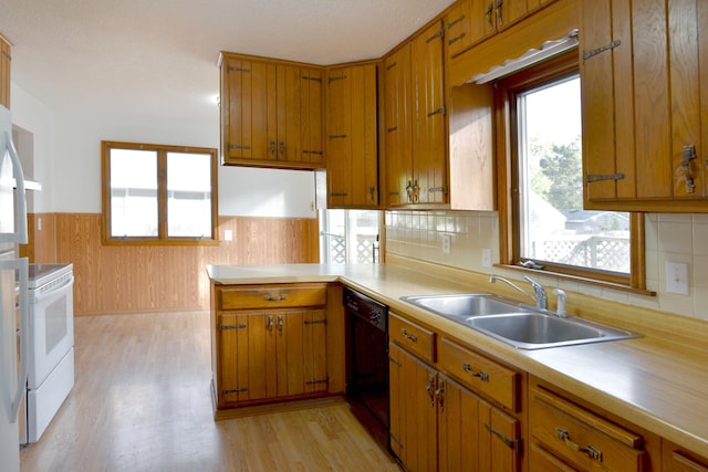 kitchen featuring black dishwasher, a sink, electric stove, light countertops, and wainscoting