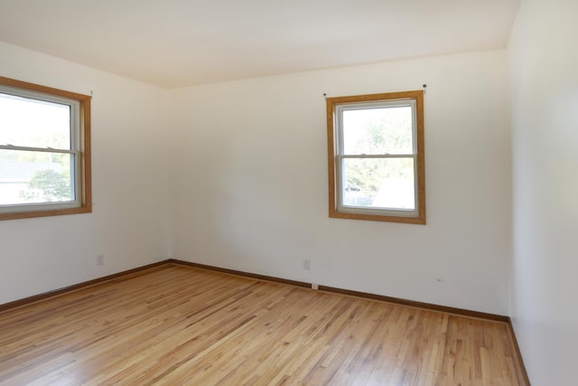 spare room featuring light wood-style floors and baseboards