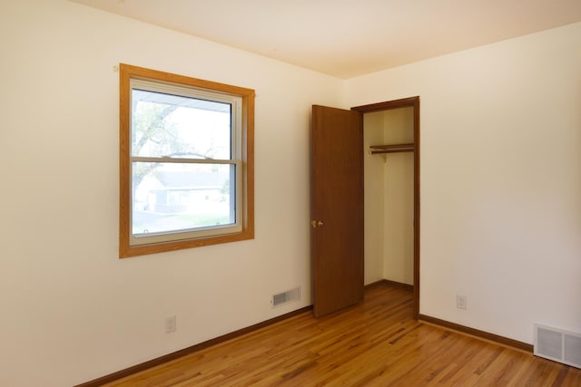 unfurnished bedroom with light wood-style floors, baseboards, and a closet