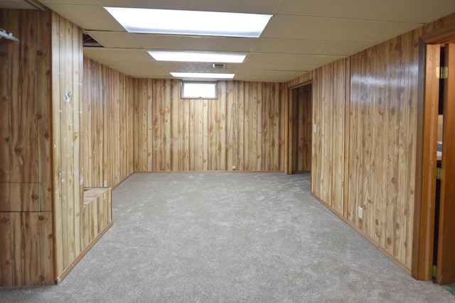 below grade area featuring carpet, wooden walls, and a paneled ceiling