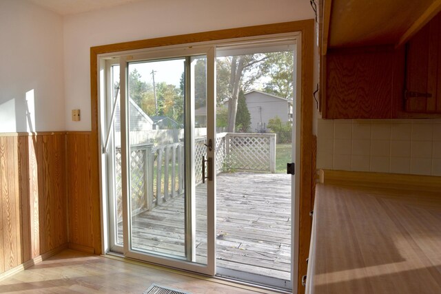 doorway to outside featuring healthy amount of natural light, wooden walls, and wood finished floors