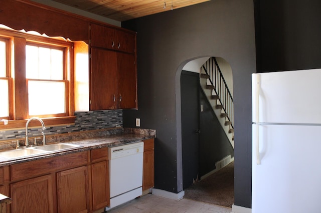 2612 3rd Ave W, Hibbing, MN 55746 - kitchen with white appliances, tasteful backsplash, dark countertops, arched walkways, and brown cabinetry