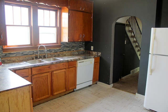 2612 3rd Ave W, Hibbing, MN 55746 - kitchen featuring white appliances, brown cabinetry, decorative backsplash, and arched walkways