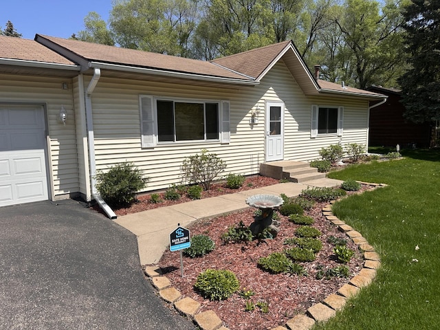 view of front of home with a front lawn, a shingled roof, an attached garage, and asphalt driveway