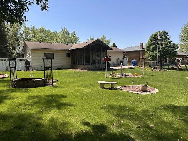 rear view of property featuring an outdoor fire pit and a sunroom
