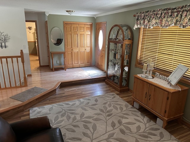 entryway with ornamental molding, light wood-style floors, and baseboards