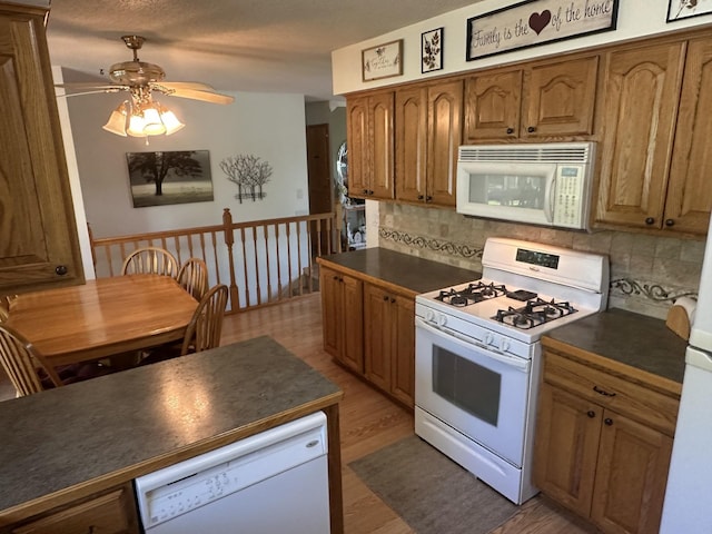 kitchen featuring white appliances, dark countertops, and ceiling fan