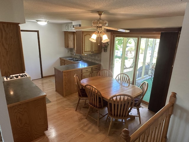 dining space with a ceiling fan, light wood finished floors, and a textured ceiling