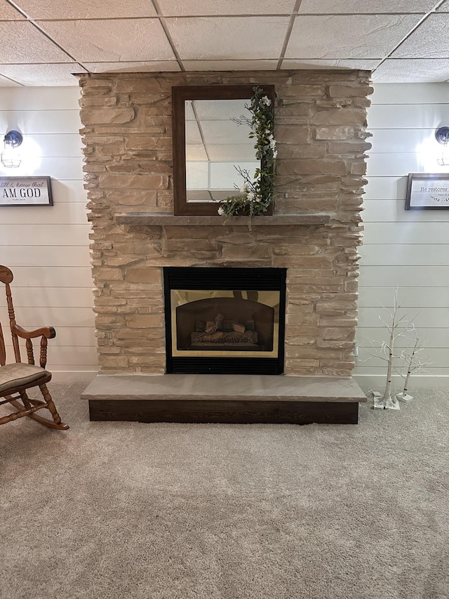 detailed view of carpet, a fireplace, a paneled ceiling, and wooden walls