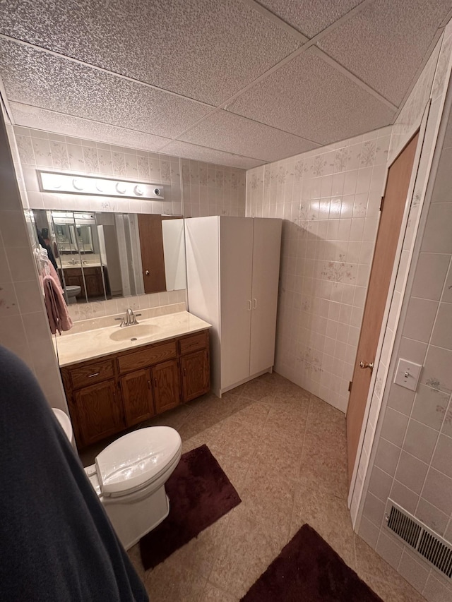 bathroom with tile walls, vanity, and toilet