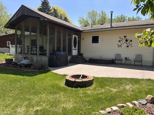 rear view of property with a sunroom, an outdoor fire pit, a yard, a patio, and roof with shingles