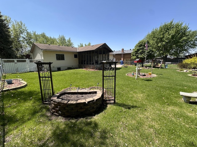 view of yard with a playground, a sunroom, and a fire pit