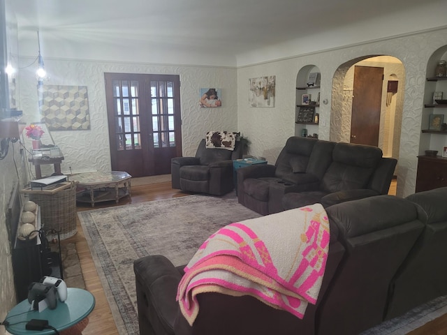 living room featuring a textured wall, wood finished floors, and arched walkways