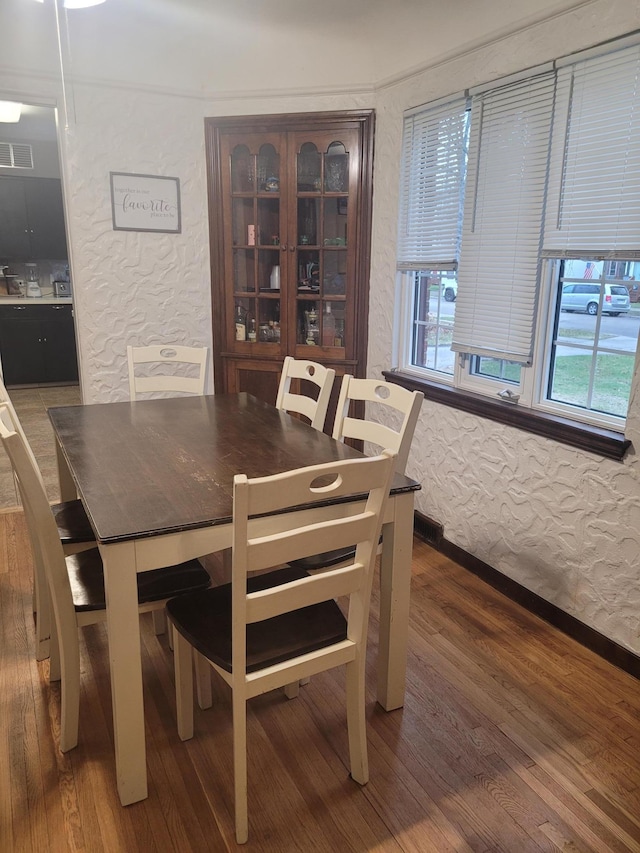dining area featuring wood finished floors and a textured wall