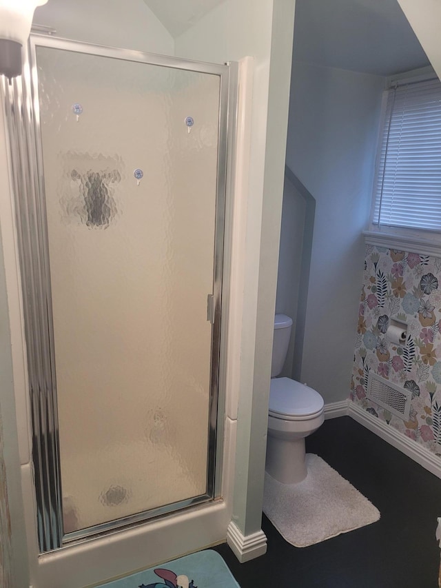 bathroom with baseboards, toilet, and a stall shower