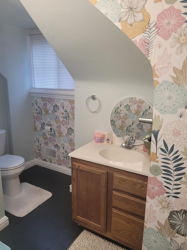 half bath featuring toilet, vanity, and baseboards