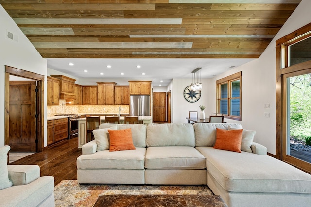 living room with dark wood finished floors, recessed lighting, vaulted ceiling, and a chandelier