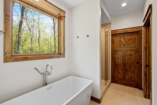 bathroom featuring plenty of natural light, a freestanding tub, a shower stall, and recessed lighting