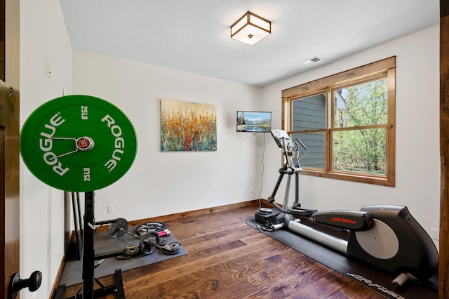 exercise area with wood finished floors, baseboards, and a textured ceiling