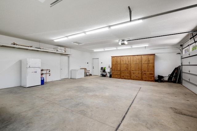 garage featuring freestanding refrigerator and a garage door opener