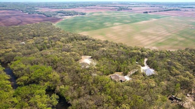 view of rural area featuring a heavily wooded area and abundant farmland