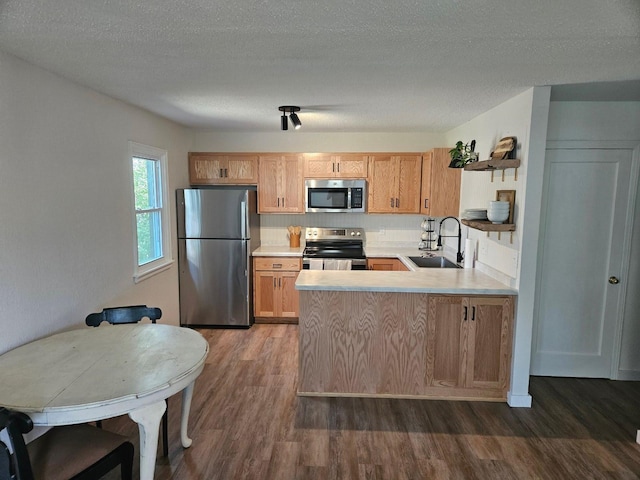 kitchen featuring appliances with stainless steel finishes, a sink, dark wood-style flooring, light countertops, and a textured ceiling