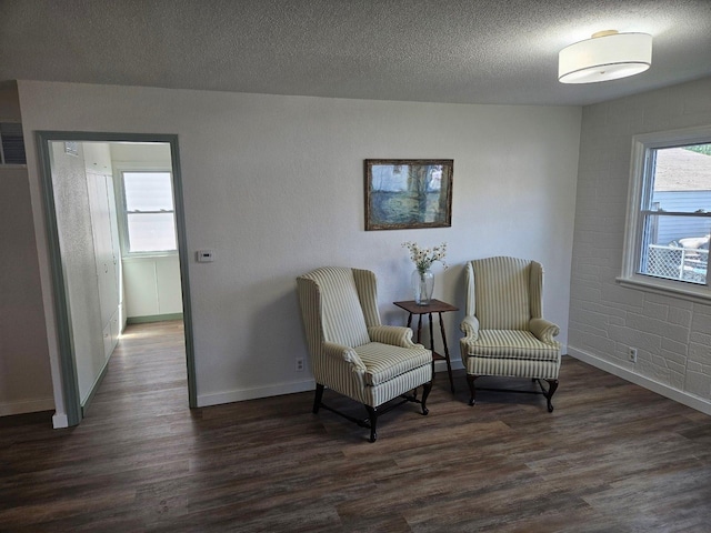 sitting room with dark wood finished floors, baseboards, healthy amount of natural light, and a textured ceiling