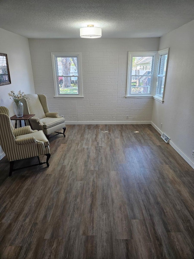 living area featuring dark wood-style flooring, baseboards, plenty of natural light, and a textured ceiling