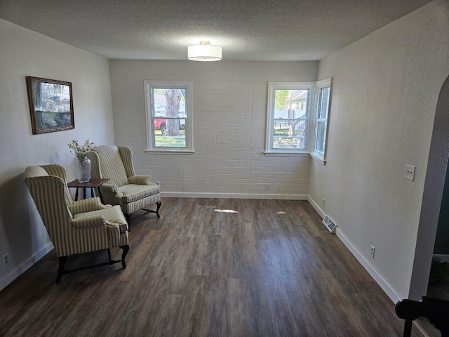 sitting room with dark wood-style floors, baseboards, and a textured ceiling