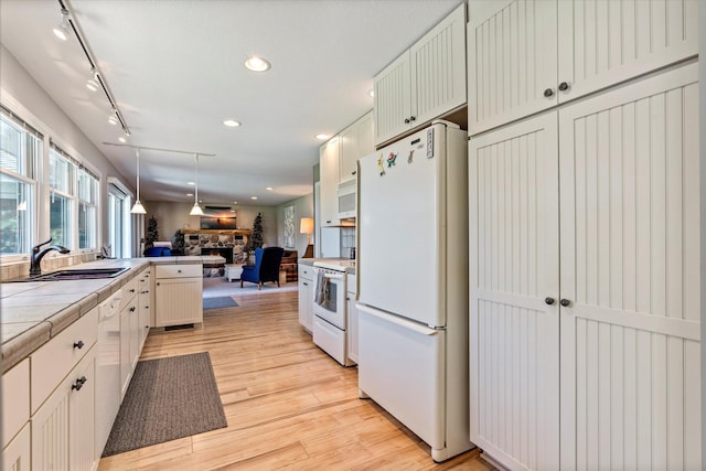 kitchen featuring white appliances, a fireplace, open floor plan, tile countertops, and a sink