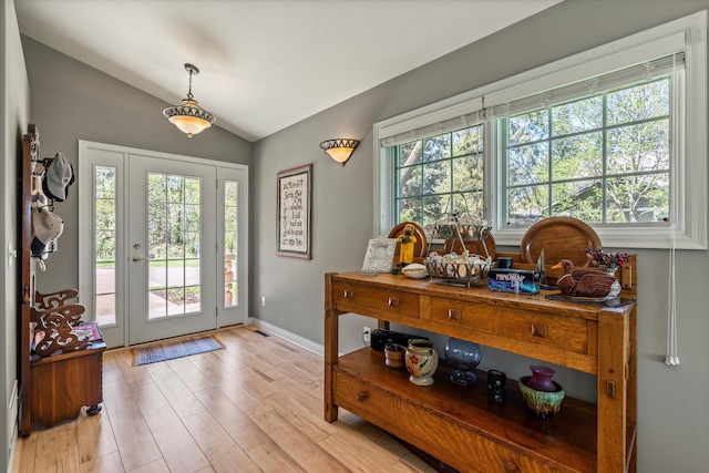 entryway featuring healthy amount of natural light, lofted ceiling, light wood finished floors, and baseboards