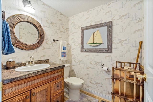 half bathroom featuring wallpapered walls, toilet, vanity, and baseboards