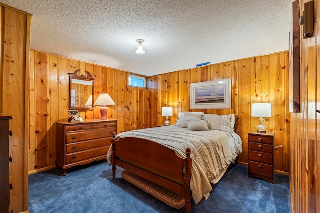 bedroom with dark carpet, wood walls, and a textured ceiling