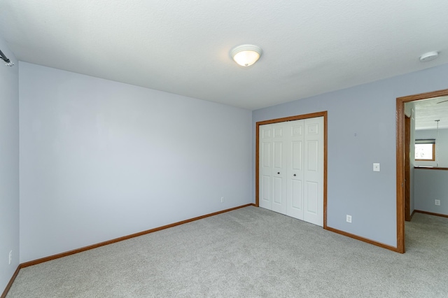 unfurnished bedroom featuring carpet floors, baseboards, and a closet