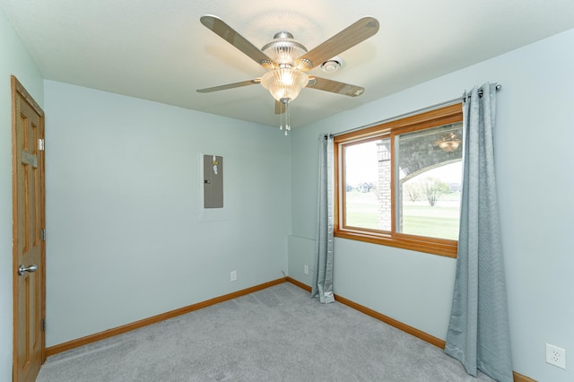 spare room featuring electric panel, baseboards, ceiling fan, and light carpet
