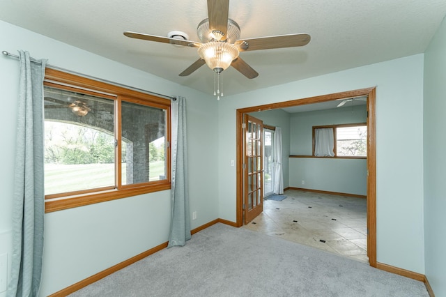 carpeted empty room with baseboards and a ceiling fan
