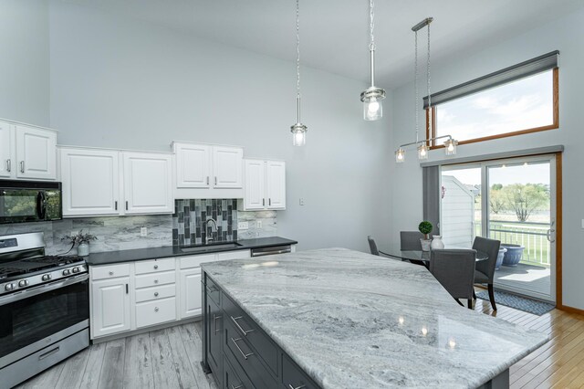 1463 Belvior Ln NE, Byron, MN 55920 - kitchen with gas stove, black microwave, a sink, a towering ceiling, and decorative backsplash