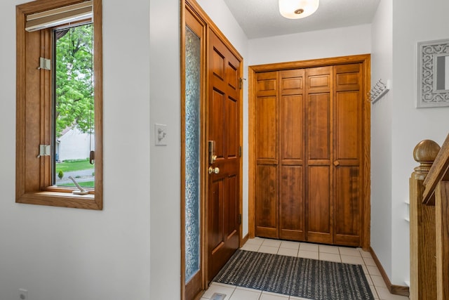 foyer entrance featuring light tile patterned floors and baseboards