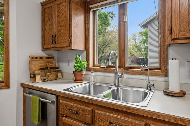 kitchen featuring a sink, brown cabinetry, dishwasher, and light countertops