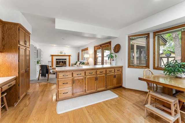 kitchen with a peninsula, light wood finished floors, open floor plan, and brown cabinets