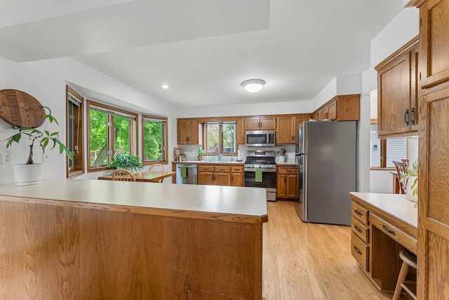 kitchen featuring appliances with stainless steel finishes, a sink, light countertops, and brown cabinets