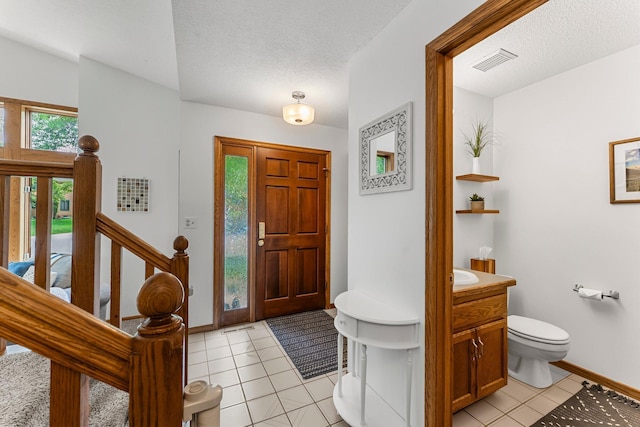 entryway with light tile patterned flooring, baseboards, and a textured ceiling