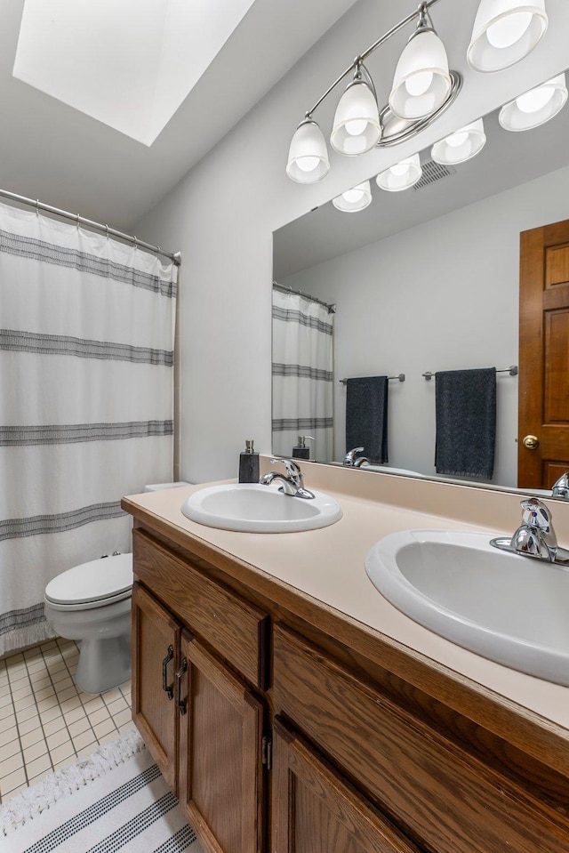 bathroom featuring double vanity, toilet, a skylight, and tile patterned flooring