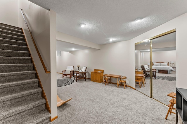 sitting room with carpet floors, stairway, a textured ceiling, and baseboards