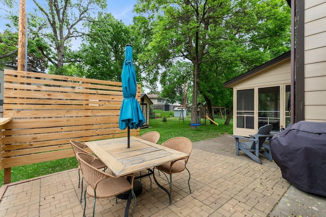 view of patio with outdoor dining space, a sunroom, a playground, and grilling area