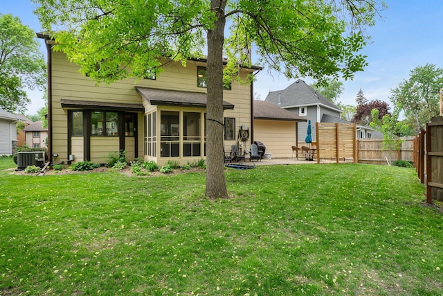 back of property with central air condition unit, a patio area, a sunroom, and a shingled roof