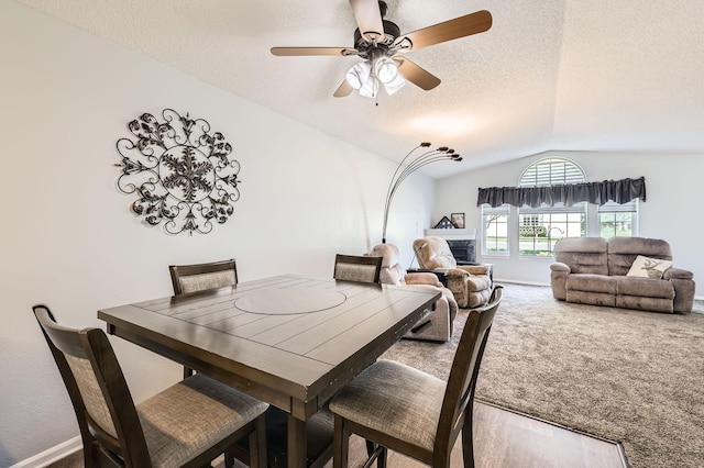 dining area featuring lofted ceiling, a textured ceiling, carpet, and a ceiling fan