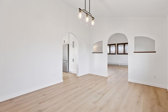 19835 County Road 30, Corcoran, MN 55340 - spare room featuring a baseboard heating unit, arched walkways, light wood-type flooring, and baseboards