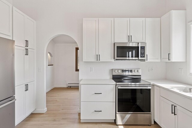 19835 County Road 30, Corcoran, MN 55340 - kitchen with appliances with stainless steel finishes, white cabinets, a baseboard radiator, light countertops, and light wood finished floors